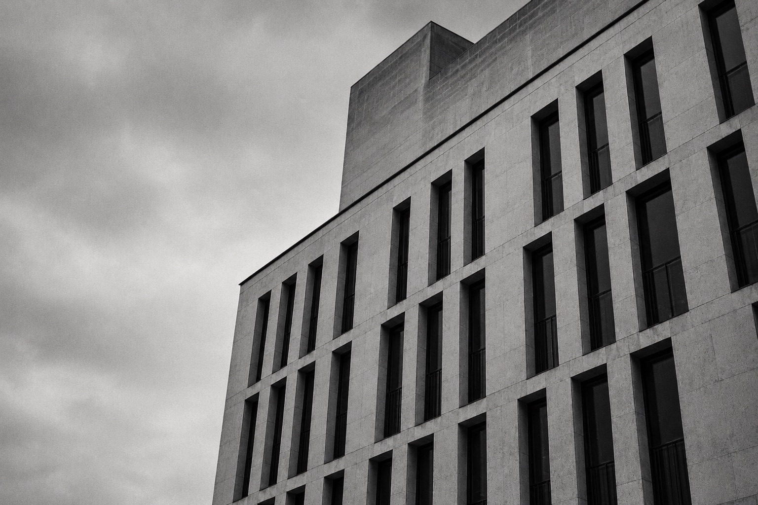 A stone institutional building photographed from a low angle under an overcast sky.